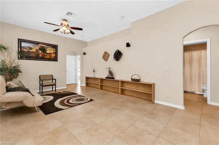 Spacious interior featuring tile flooring throughout, a ceiling fan with integrated lighting, and neutral wall tones