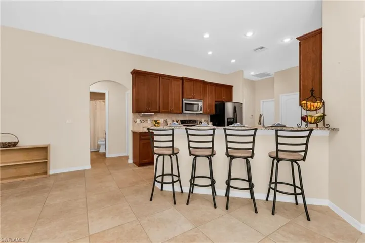 Kitchen featuring wood cabinetry, stainless steel appliances, and a breakfast bar with a stone-look countertop