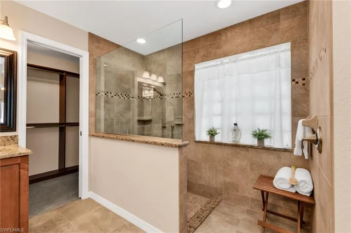 Shower with full-height tile surround, glass enclosure, and decorative accent tiles
