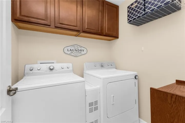 Dedicated laundry area featuring upper wood-finish cabinetry, a washer and dryer, and neutral wall tones