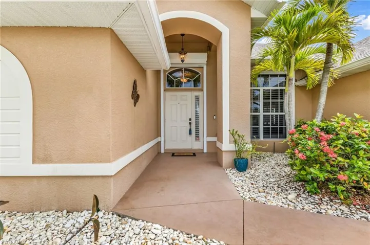 Arched entryway with a decorative transom window, white paneled front door, and a hanging pendant light fixture