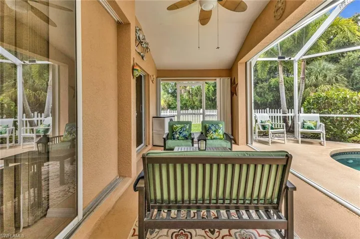 Screened lanai featuring a vaulted ceiling with a fan, textured walls, and a concrete patio surrounding a curved pool