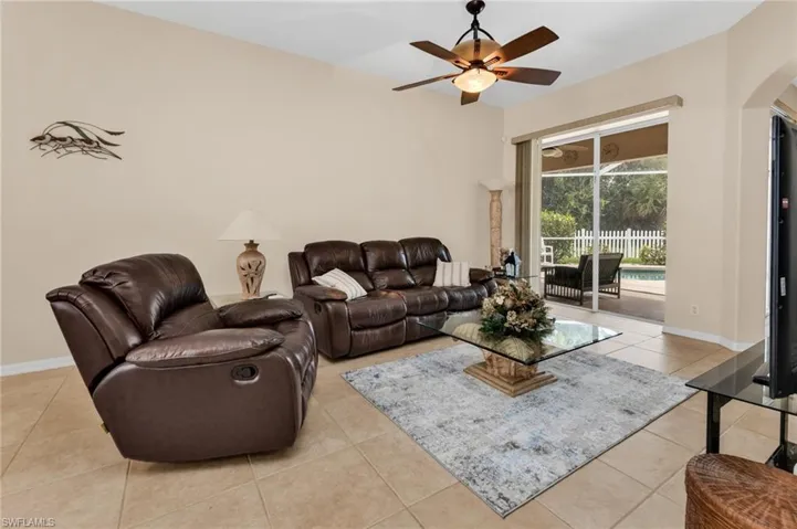 Living area featuring tile flooring, neutral wall tones, a ceiling fan with integrated lighting, and direct access to an outdoor screened lanai