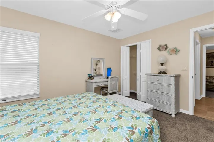 Carpeted room featuring a ceiling fan with integrated lighting, a window with horizontal blinds, and a bifold closet door