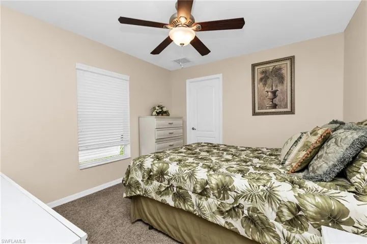 Bedroom featuring neutral wall paint, a ceiling fan with light fixture, and textured carpet flooring