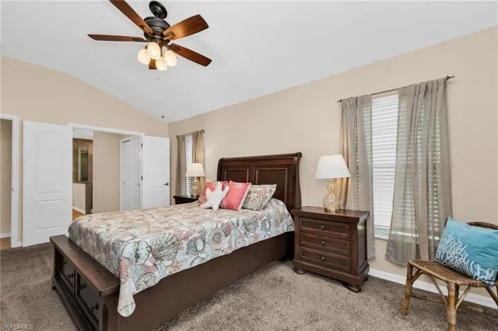 Carpeted room with a vaulted ceiling and ceiling fan with integrated lighting