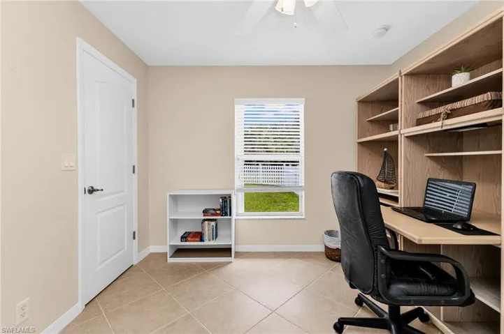 Neutral tone wall color, tile flooring, built-in shelving, ceiling fan, and window with horizontal blinds