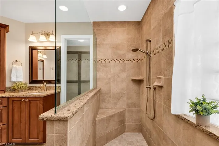 Walk-in shower featuring a built-in bench, decorative tile accent band, and a handheld shower fixture