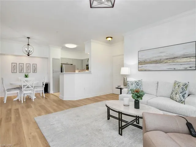 Living room featuring light wood-style floors, a chandelier, and crown molding
