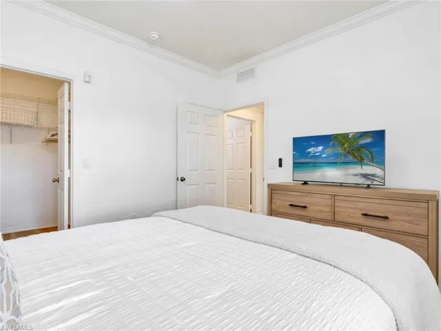 Bedroom featuring a walk in closet and crown molding