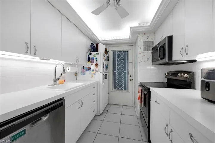 Kitchen featuring appliances with stainless steel finishes, light countertops, white cabinetry, and tile walls