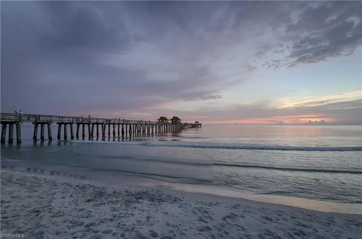 Dock area featuring view of water and beach and a pier