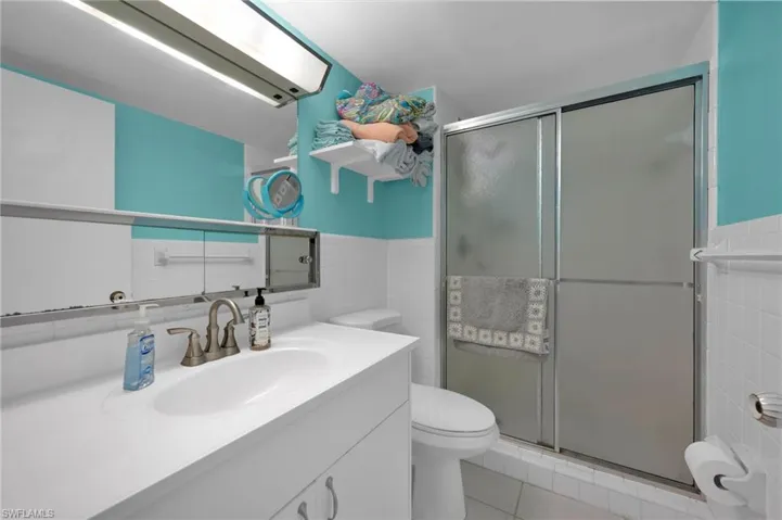 Bathroom with tile walls, vanity, light tile patterned floors, and a shower stall