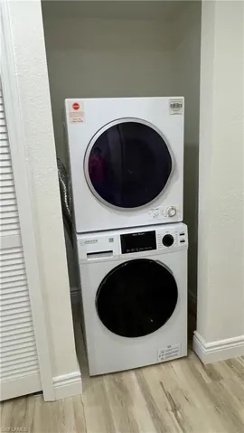 Laundry area featuring light hardwood / wood-style floors and stacked washer / dryer