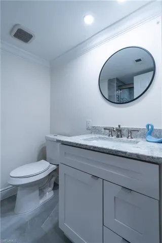 Bathroom with vanity, ornamental molding, and toilet
