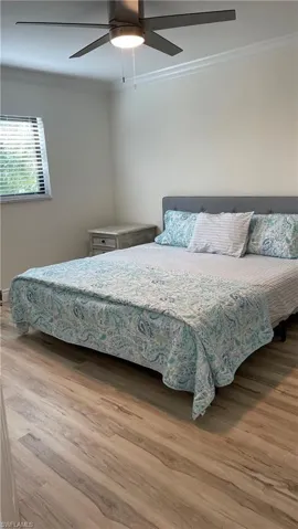 Bedroom with ceiling fan, crown molding, and hardwood / wood-style flooring