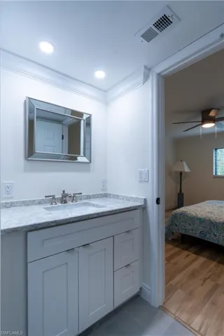 Bathroom with crown molding, ceiling fan, vanity, and hardwood / wood-style floors