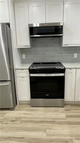 Kitchen featuring backsplash, white cabinetry, and stainless steel appliances