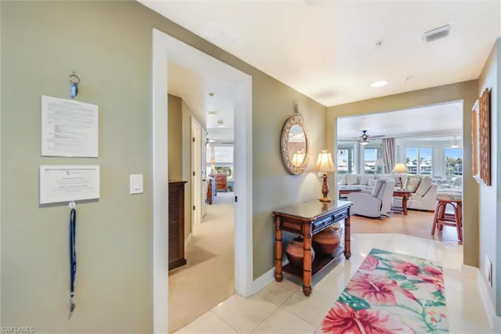 Hallway featuring light tile patterned floors and light colored carpet