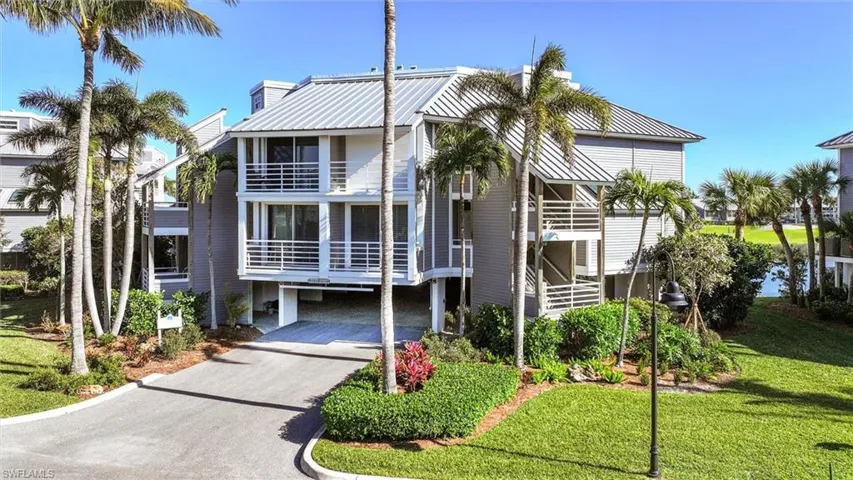 Beach home featuring driveway, a front yard, a balcony, and a chimney