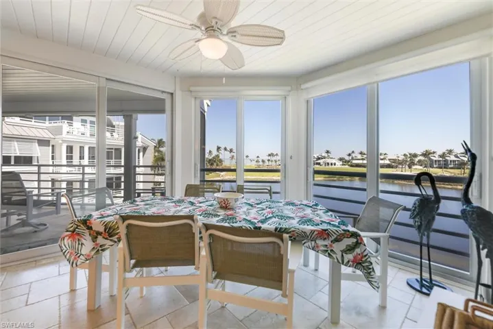 Sunroom with a water view, a residential view, and wood ceiling