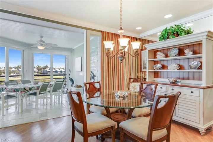 Dining area featuring ceiling fan, crown molding, light wood-type flooring, and suspended lighting