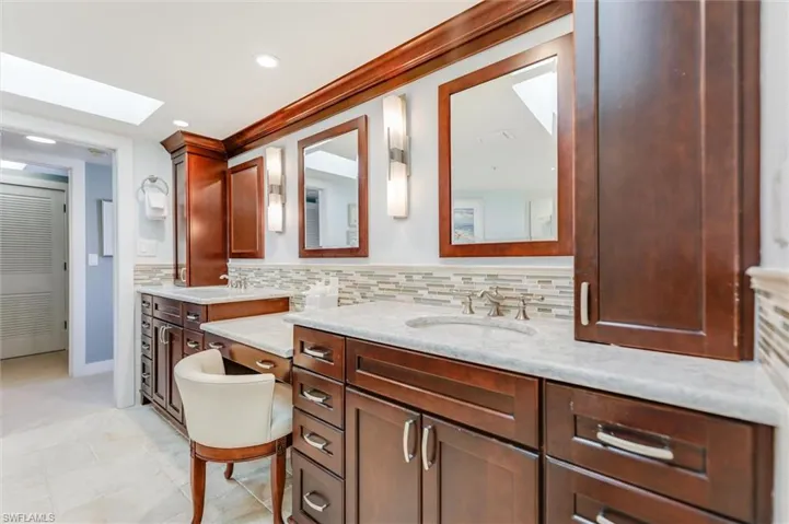 Bathroom featuring double vanity, decorative backsplash, a skylight, and recessed lighting