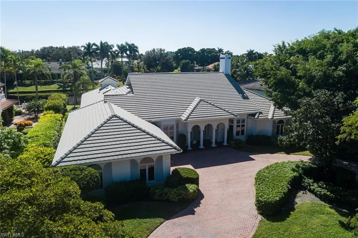 View of front of property featuring decorative driveway, a chimney, and a tile roof