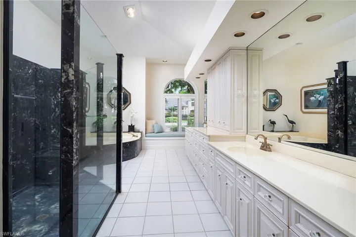 Bathroom with a bath, vanity, a marble finish shower, light tile patterned flooring, and lofted ceiling