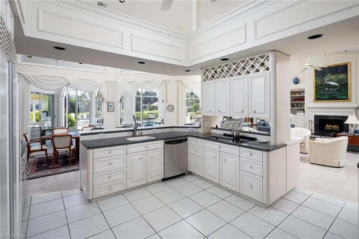 Kitchen featuring open floor plan, a towering ceiling, a ceiling fan, white cabinetry, and appliances with stainless steel finishes