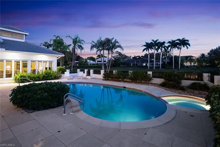 Pool at dusk featuring a patio and a pool with connected hot tub