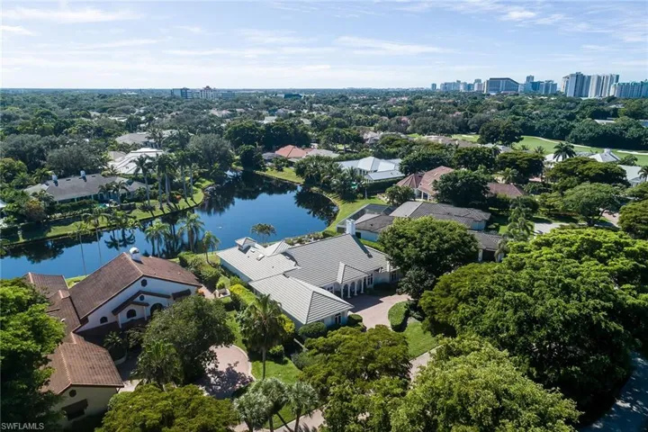 Aerial view of residential area with a large body of water and a tree filled landscape