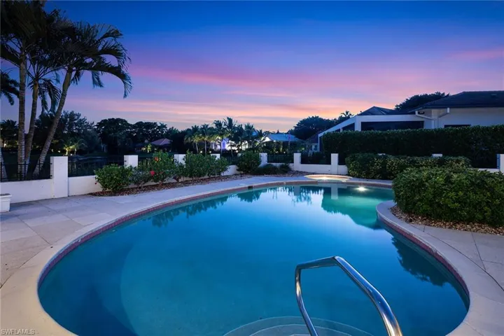 Pool at dusk with a fenced backyard and a patio area