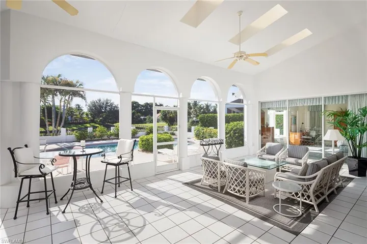 Sunroom / solarium with plenty of natural light, high vaulted ceiling, tile patterned flooring, and a skylight