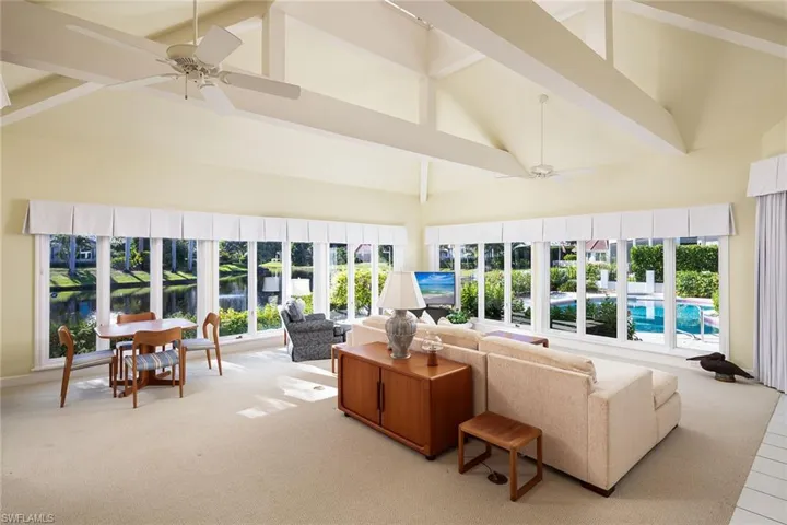 Sunroom / solarium featuring a towering ceiling, carpet flooring, and beam ceiling