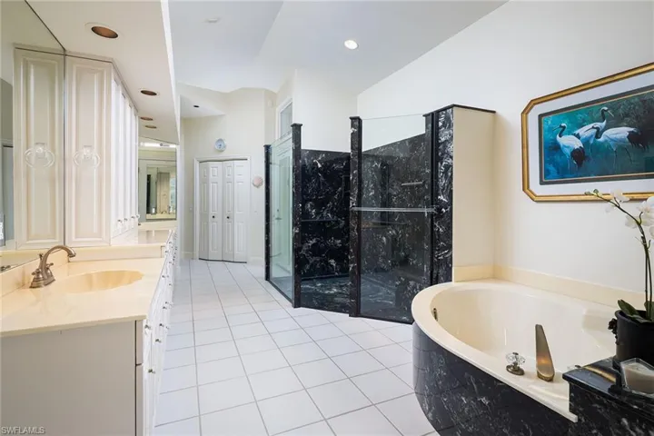 Full bathroom with double vanity, a bath, light tile patterned floors, a closet, and a marble finish shower