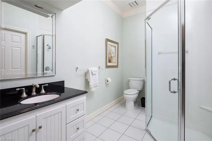 Bathroom featuring a shower stall, vanity, light tile patterned floors, and crown molding
