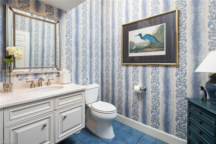 Half bath featuring vanity, wallpapered walls, and dark tile patterned floors