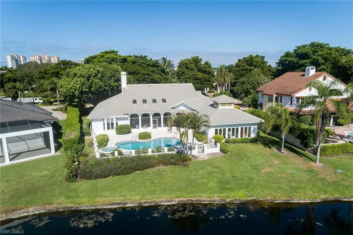 Back of property with a sunroom, a patio, a yard, an outdoor pool, and a water view