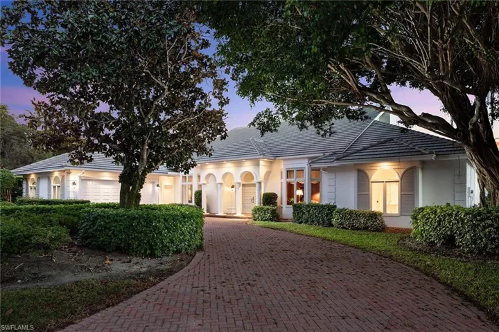 View of front of home with decorative driveway, a tile roof, stucco siding, and a garage