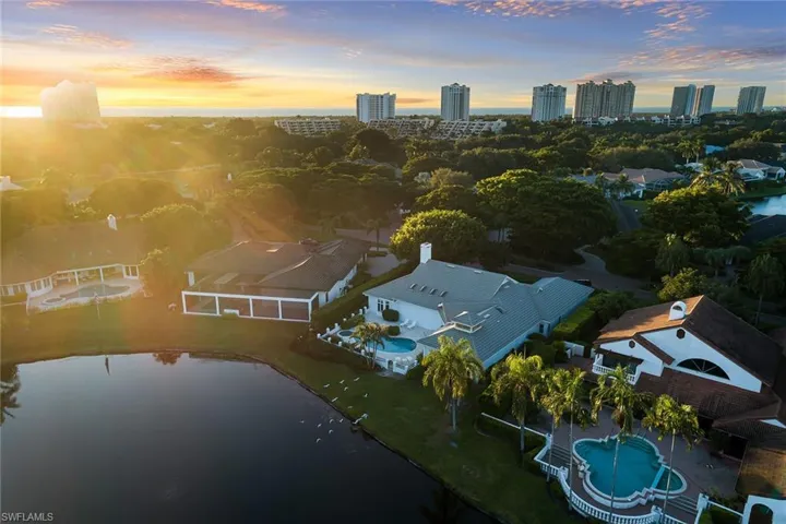 Aerial view at dusk of view of pool area, a water view, and a view of city