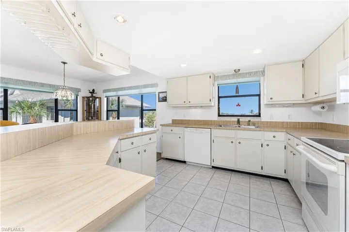Kitchen with light countertops, white appliances, pendant lighting, and plenty of natural light
