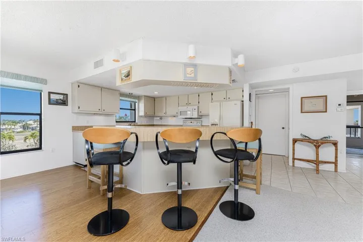 Kitchen with white appliances, a kitchen breakfast bar, light countertops, and cream cabinets