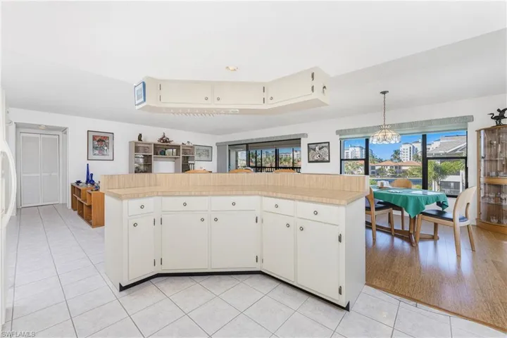 Kitchen with light tile patterned floors, white cabinets, a kitchen island, a chandelier, and freestanding refrigerator