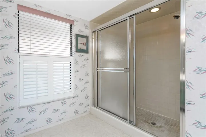Bathroom featuring wallpapered walls and a stall shower