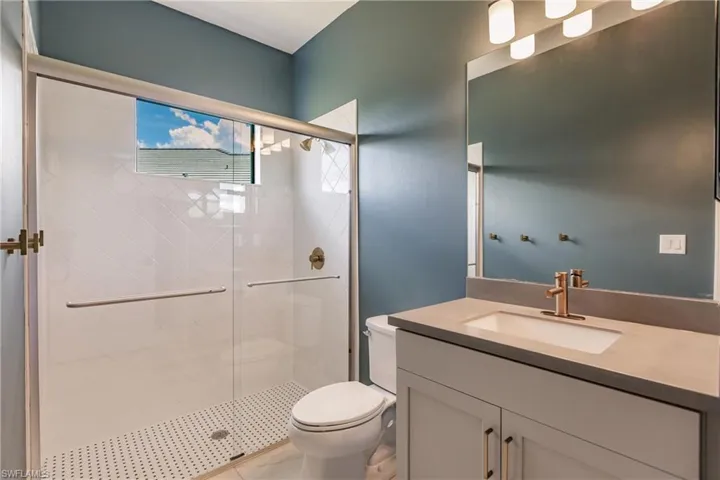 Bedroom 2 full bath with glass shower doors and solid surface vanity.