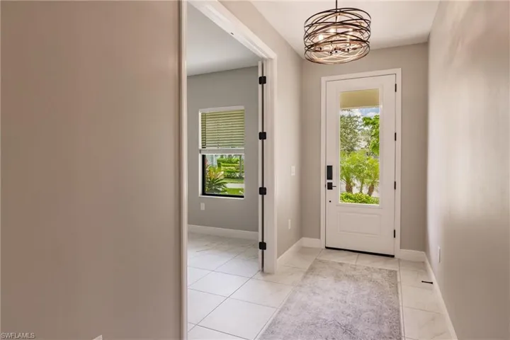 Whole home tile begins in the foyer. Custom chandelier and den/leisure room is on the left in photo.