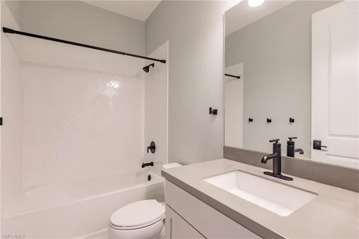 Guest suite bath with tiled tub/shower and solid surface vanity.