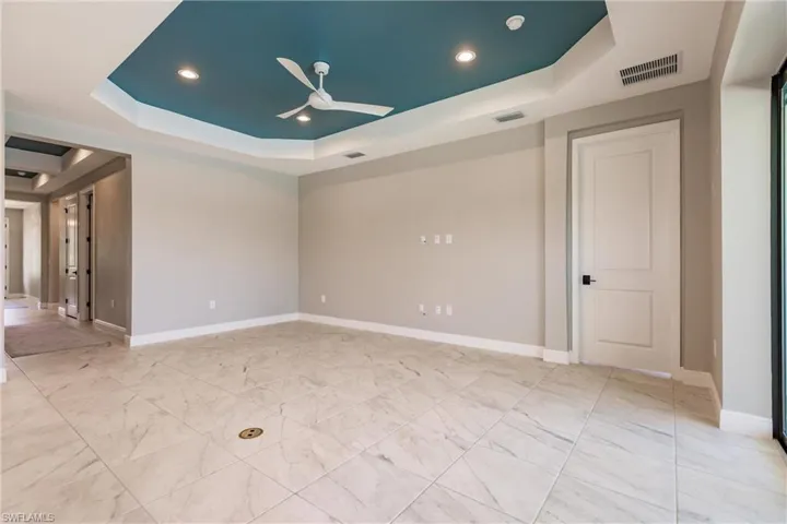 Great room is located in the rear of the home for easy pool access and views of lake. Primary bedroom door shown on right in the photo.