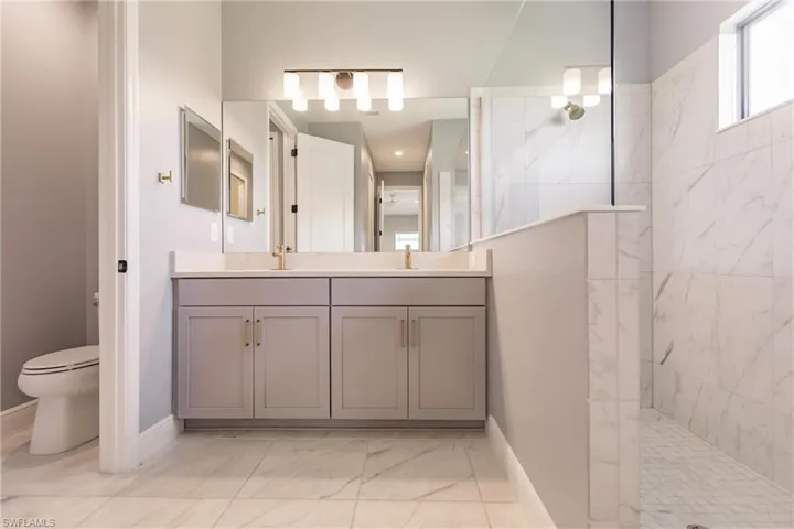 Primary bath with tiled walk-in shower and double sinks.